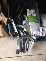 Bin containing various steel and chrome utility wall brackets with some white finished steel shelf and rod brackets in original packaging.