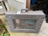 Closed grey hard plastic Mastercraft branded carrying case with transparent window showing air hose inside