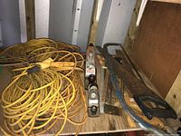 Photo showing yellow extension cords and some of the hand planes and hand saws on a wooden surface in a shed environment.
