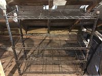 Front view of a coated metal utility rack showing four wire mesh shelves and coated metal frame.