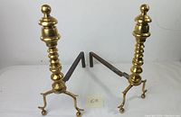 Pair of brass fireplace andirons showing front uprights and cast-iron horizontal supports