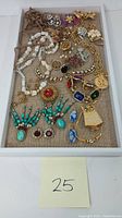 Full view of costume jewelry pieces on tray showing variety of brooches, necklaces and earrings with colorful stones and beads