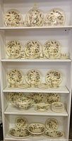 Four-shelf display of Gien Corne d'Abondance patterned dinnerware showing plates, cups, saucers and service pieces.