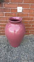 Full view of the large ceramic planter vase against a brick wall, showing the overall shape, glaze color, and condition.