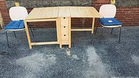 Wide shot of table with extended side panels and two chairs with blue cushions on either side