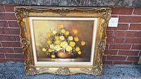 Framed oil painting showing full artwork with ornate gold frame against brick background.