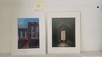 Two serigraph art prints placed side by side, showing images of the Brooklyn Bridge and candlelight room with visible pencil signatures.