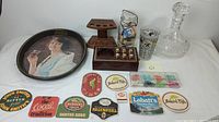 Lot layout showing crystal decanter, Coca-Cola tray, wooden pipe holders, coasters and brand labels