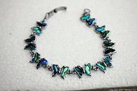 Full length view of the silver tone butterfly bracelet featuring colorful abalone shell inlays on each butterfly charm.