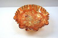 Orange iridescent glass bowl with scalloped rim and raised floral rose pattern.
