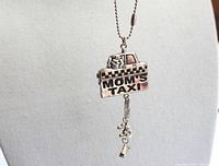 Close-up of the silver-tone 'MOM'S TAXI' taxi car keychain charm showing paw and bone dangling charms.