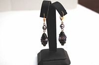 Pair of lamp work glass earrings displayed on a black earring holder, showing their length and design.