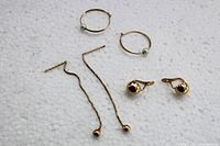 All three pairs of 10K gold earrings shown together on white surface, includes pearl hoops, long drop chains with balls, and gold ball clip-ons.