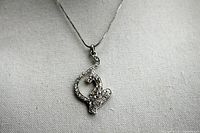 Necklace with rhinestone-encrusted cat pendant hanging from silver-tone chain on neutral fabric background.