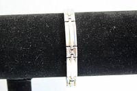 Silver tone bracelet displayed on black jewelry stand showing linked rectangular segments.