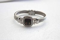 Silver tone bracelet on white background showing the faceted dark topaz brown square stone set in the center, bordered by clear rhinestones and double cable-style band.