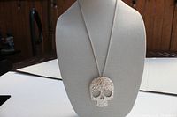 Full view of silver tone filigree skull pendant necklace displayed on a mannequin bust against neutral background