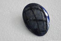 Close-up of the polished sodalite stone brooch showing surface details and a small chip on one side.