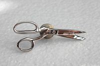 Close-up photo of the sterling silver scissor-shaped pin showing blade detail and stamping.