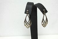 Front view of sterling silver teardrop style earrings displayed on a black stand showing the cut-out design and polished finish.