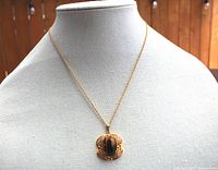 Full view of the tiger eye pendant necklace displayed on bust showing chain length and pendant size.