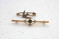 Two Victorian 14K gold pins shown from top view on white surface, highlighting the pearls and green gemstone.