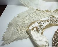 Two lace collars in delicate cream lace with scalloped edges, shown with a gold-tone embellishment on one collar