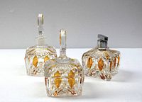 Front view of three-piece vintage dressing table set showing perfume bottle with dabber lid, atomizer without bulb pump, and jewelry jar with lid. Diamond cut clear glass with yellow glass accents.