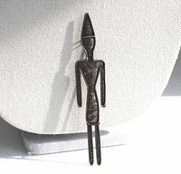 Front view of the vintage tall figure brooch showing its darkened patina and slender design against a neutral backdrop.