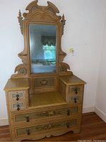 Full view of antique Victorian-style wooden vanity dresser with mirror, showing floral painted decorations, multiple drawers, and wear on wood.