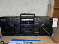 Front view of Sony CFD-440 boom box showing stereo speakers, cassette deck, control buttons, and radio tuner.