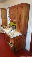 Full view of oak Hoosier style cabinet showing upper cupboards, pull-out porcelain work surface and lower storage