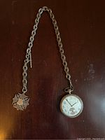 Full view of pocket watch, chain and fob laid flat