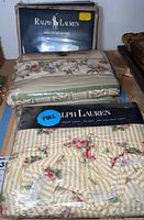 Photo showing Ralph Lauren packaged bed linens and floral pattern sheets, including a full flat sheet with yellow stripes and pink roses.