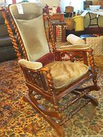 Side angle view showing the full rocker base, twisted spindle arms and legs, padded backrest, and removable cushion seat.