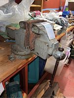 Side view showing the vise body, the wooden jaw covers, and the handle with rust.