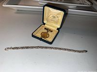 Overall view of sterling silver bracelet and 10K gold medal pin in presentation box