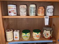 Shelf with a variety of vintage tea tins, marmalade jars including James Keiller's Dundee marmalade jars, and biscuit tins with floral and fruit designs.