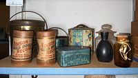 Shelf display showing two Edison Gold Moulded Records cylindrical tins, one turquoise Edgeworth Extra Plug Slice tin, and three vintage glass bottles in various styles and sizes.