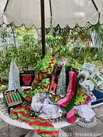 Overview of Christmas collectibles displayed on a table outdoors including trees, ribbon, stockings, candles, gift bags, and gnome globe.