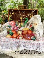 Wide view of the vintage ornament collection arranged on white cloth with wicker basket background.
