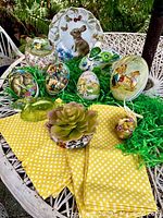 Full view of Easter collection including ceramic dishes, paper Easter eggs, napkins, bunny plate, and succulent on outdoor wicker table