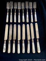 Forks and knives arranged to show mother of pearl handles with sterling silver bands and steel heads