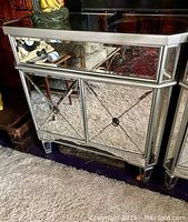 Silver mirrored console table showing front view with two doors and drawer. Mirror discoloration visible at bottom panel.