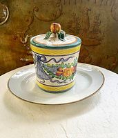 Italian ceramic kitchen canister with lid decorated with colorful floral and ribbon motifs on top of the Limoges platter.