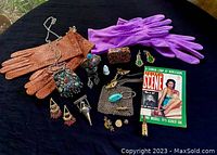 Full overview of the vintage accessory lot showing gloves, jewelry, miniature figurine, and small purses on dark cloth.