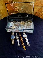 Full view showing glass display box with 10 bracelets inside and 6 watches arranged outside