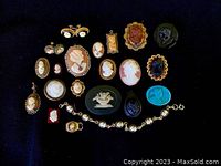 Photo showing entire vintage cameo jewelry collection on black background