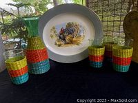 Full set showing the 4 hand-blown glasses each with colorful woven straw holders alongside the matching carafe and the large Tom Turkey platter in the background.