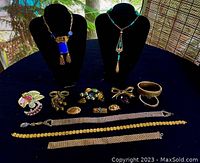Photo showing all 15 pieces of vintage jewelry laid out on dark cloth with two necklaces displayed on busts, various brooches, bracelets, rings, and small jewelry parts arranged.